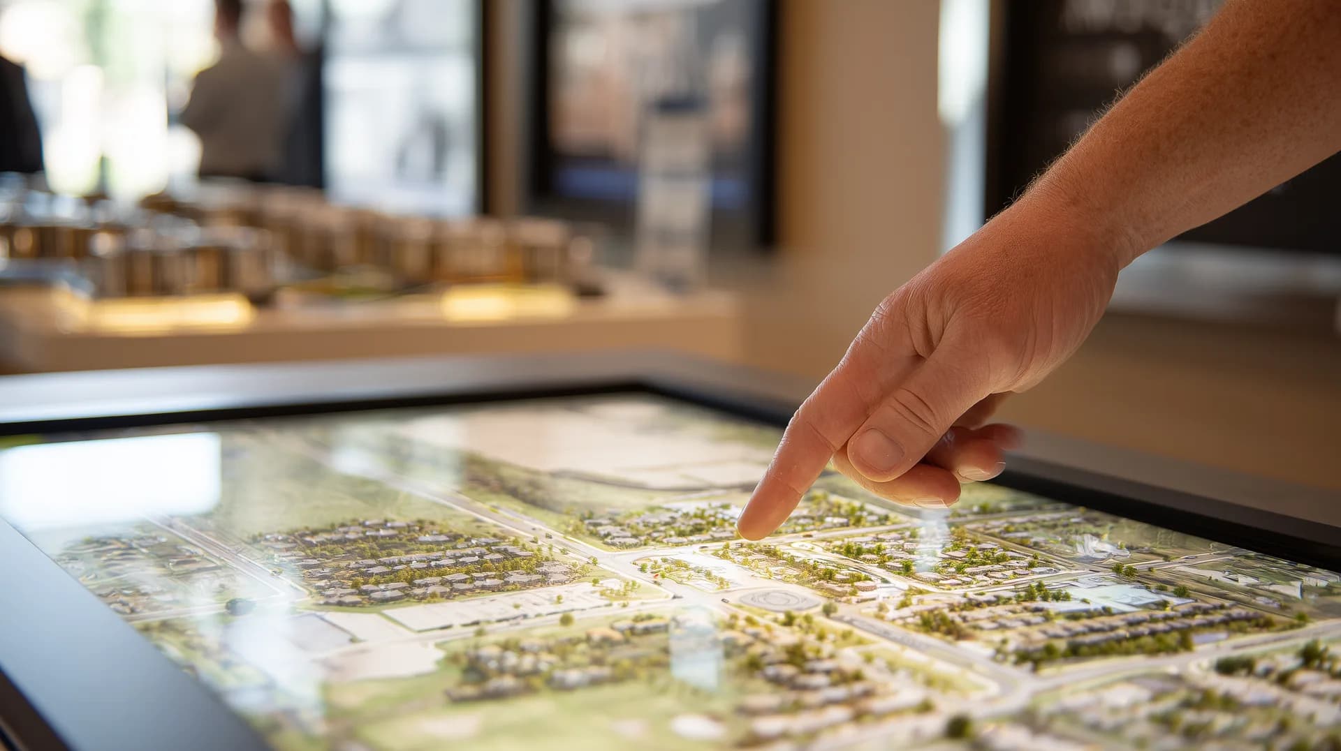 Hand pointing at a backlit community site map in a builder sales office