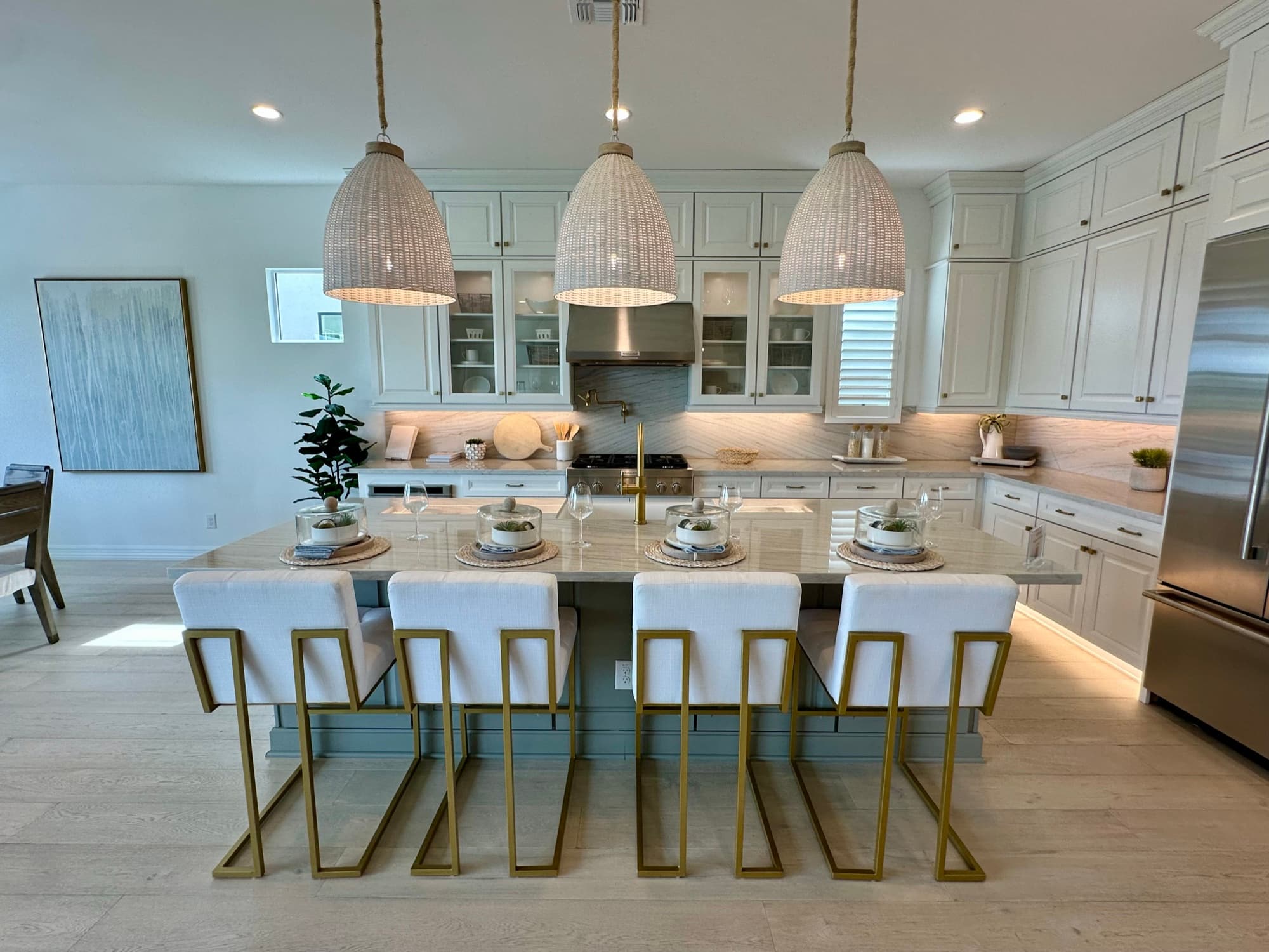 Model home kitchen with a marble island and woven pendant lights