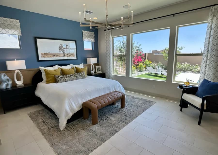Model home bedroom with blue accent wall and yard views